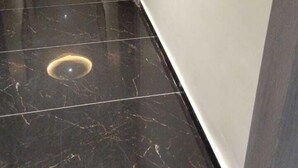 A hallway with dark marble flooring and a door at the end. - Hotel R Town (Vadodara)