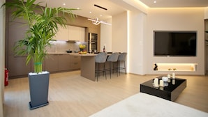 Een moderne keuken met een centraal eiland, barstoelen en een grote flatscreen televisie aan de wand.