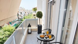 Een balkon met een tafel voor twee personen, een bloempot en uitzicht op de stad.