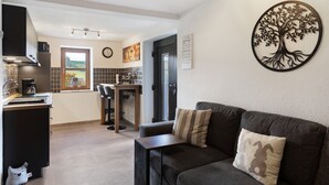 Eine moderne Küche mit Essbereich, einer Couch mit Kissen und einer Wanddekoration mit Baumdesign.