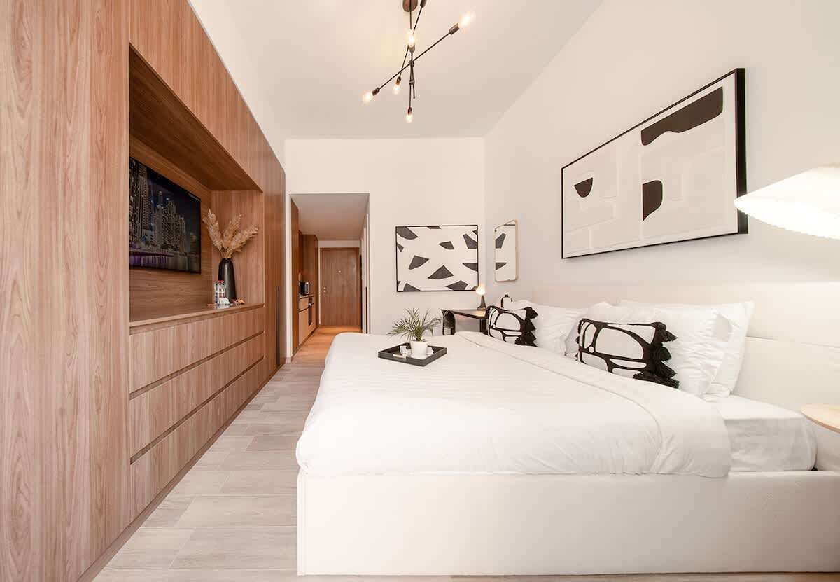 Une chambre moderne avec un grand lit, un lambris en bois et des œuvres d’art abstraites accrochées au mur.