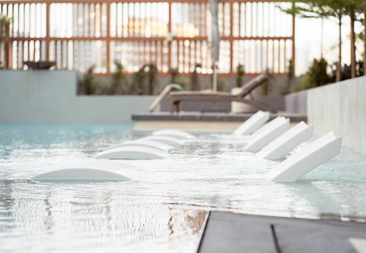 Un espace piscine avec des chaises longues et une clôture en arrière-plan.