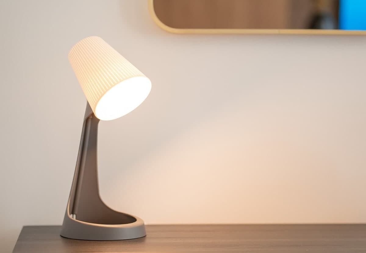 A modern desk lamp with a ribbed lampshade on a wooden surface.