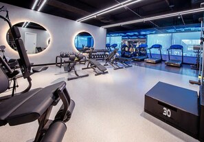 A modern gym with various exercise equipment, including treadmills and weight machines. - Hamilton House Studio: Rooftop Pool & Gym Access (Dubai)