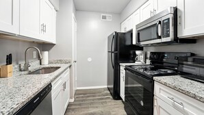 Une cuisine moderne avec des meubles blancs, un réfrigérateur en acier inoxydable, un four à micro-ondes et une cuisinière.