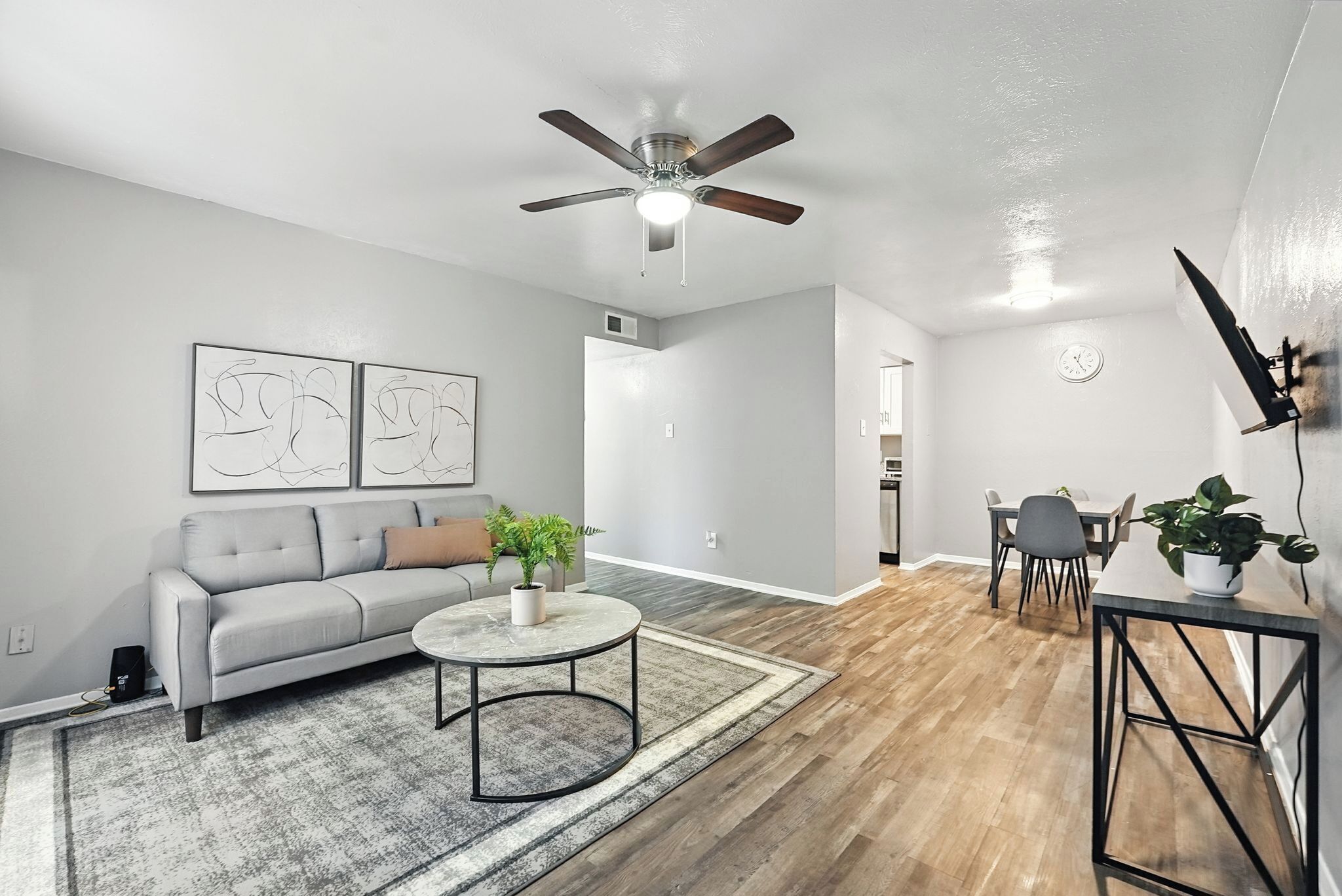 Un salon moderne avec un canapé gris, une table basse ronde et un ventilateur de plafond.
