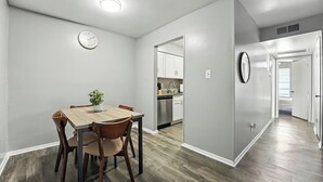 Un comedor con una mesa y sillas de madera, una planta en maceta y un reloj en la pared.