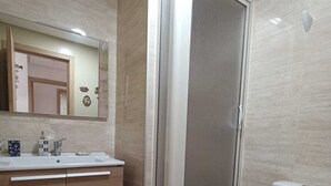 Une salle de bain moderne équipée d’une douche, de toilettes et d’un meuble-lavabo avec un miroir.