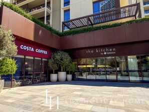 Ein Gebäude mit einem Costa Coffee und The Kitchen by Spinneys im Erdgeschoss.