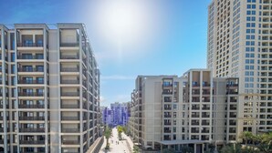 A modern residential building with multiple floors, balconies, and a central courtyard with palm trees.
