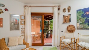 A cozy living room with a wicker sofa, a small table, and a sliding glass door leading to an outdoor patio.