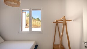 Ein Schlafzimmer mit einem Bett, einem Fenster und einem hölzernen Kleiderständer.