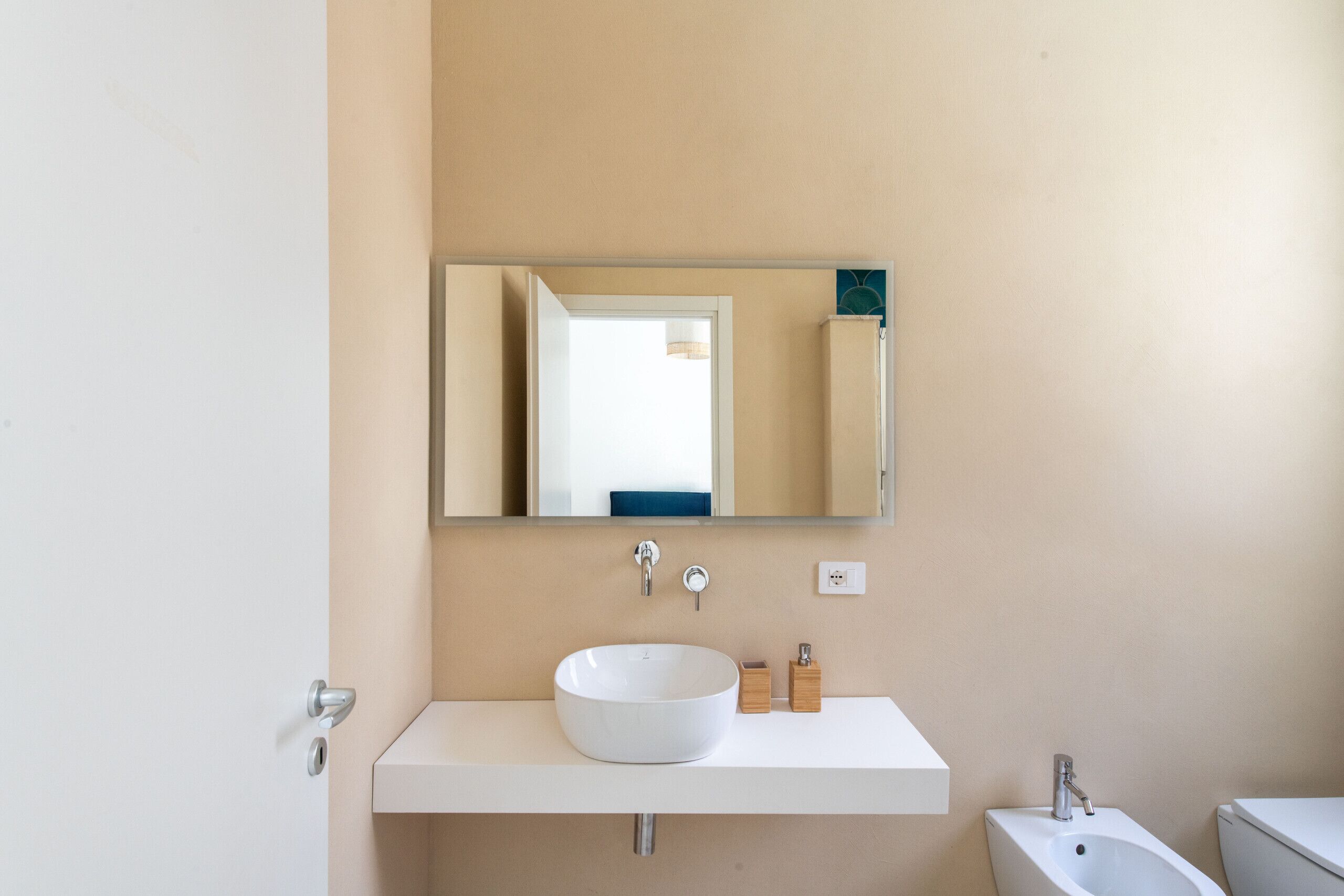 A modern bathroom with a white sink, mirror, and a bidet.