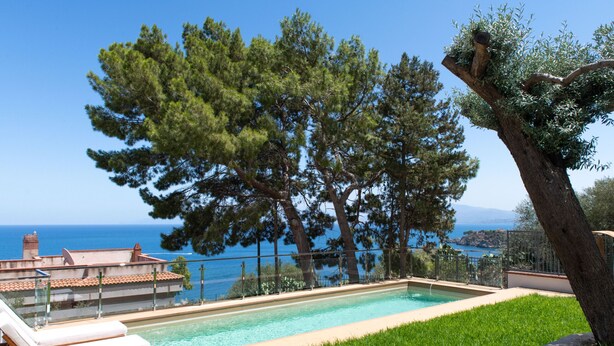 A swimming pool with a view of the sea, surrounded by trees and a fence. - Casa Solunto Vista Mare by Wonderful Italy (Santa Flavia)
