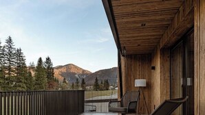 A wooden balcony with a view of mountains, a chair, a table, and a lamp. - Top 7 Geislhorn (Sankt Ulrich am Pillersee)