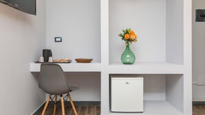 Eine moderne Küche mit weißer Arbeitsplatte, einem grünen Blumenvasen, einem weißen Kühlschrank und einem grauen Stuhl.