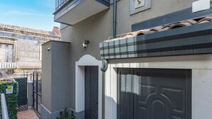 Ein Wohngebäude mit grauer Fassade, einem Ziegeldach und einer schwarzen Garagentür.