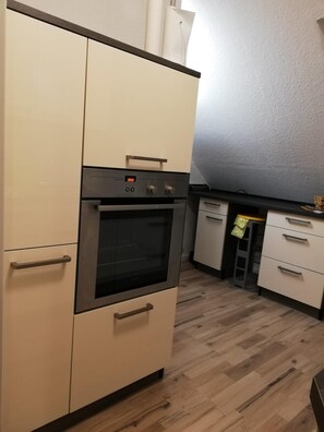Uma cozinha com forno embutido, lava-louças e piso de madeira.