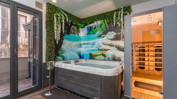 A spa room with a hot tub, a mural of a waterfall, and a sauna.