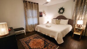 A neatly arranged bedroom with a bed, bedside lamps, a rug, and a ceiling fan.