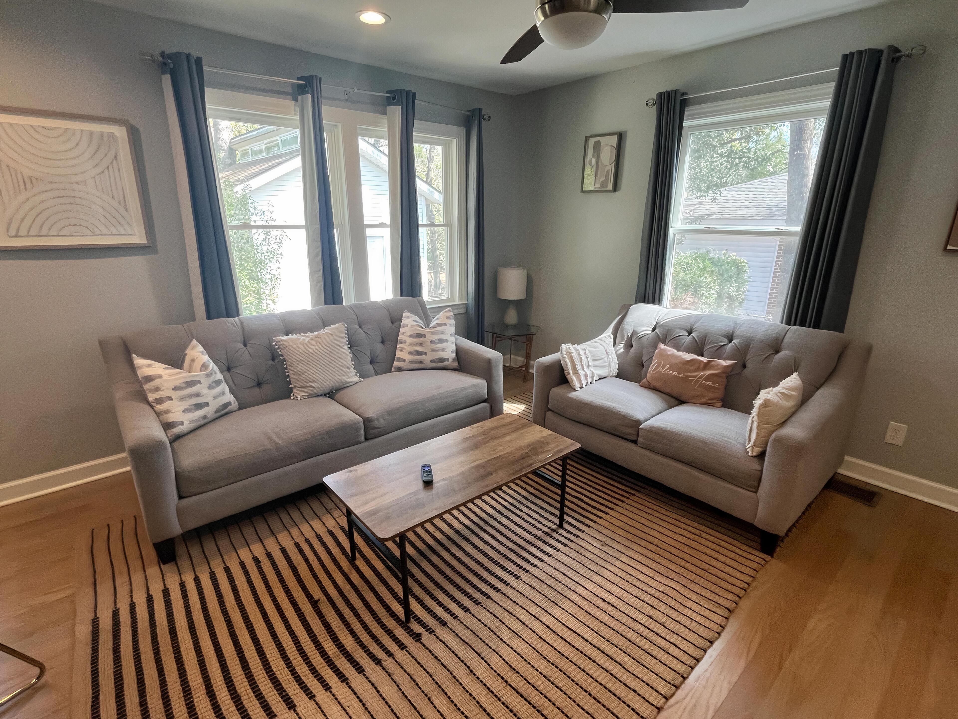 A living room with two grey sofas, a wooden coffee table, and a striped rug.