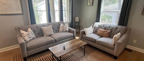 A living room with two grey sofas, a wooden coffee table, and a striped rug.