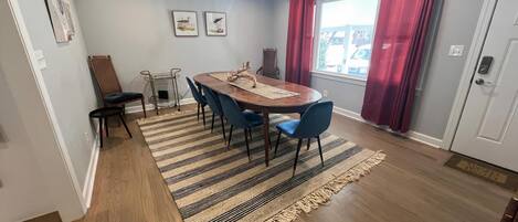 Un coin repas avec une table en bois, des chaises bleues, un tapis à rayures et un lustre.