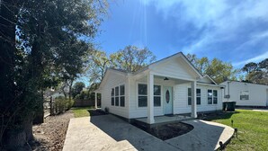 Ein eingeschossiges Haus mit überdachter Veranda, Vordergarten und blauem Himmel.