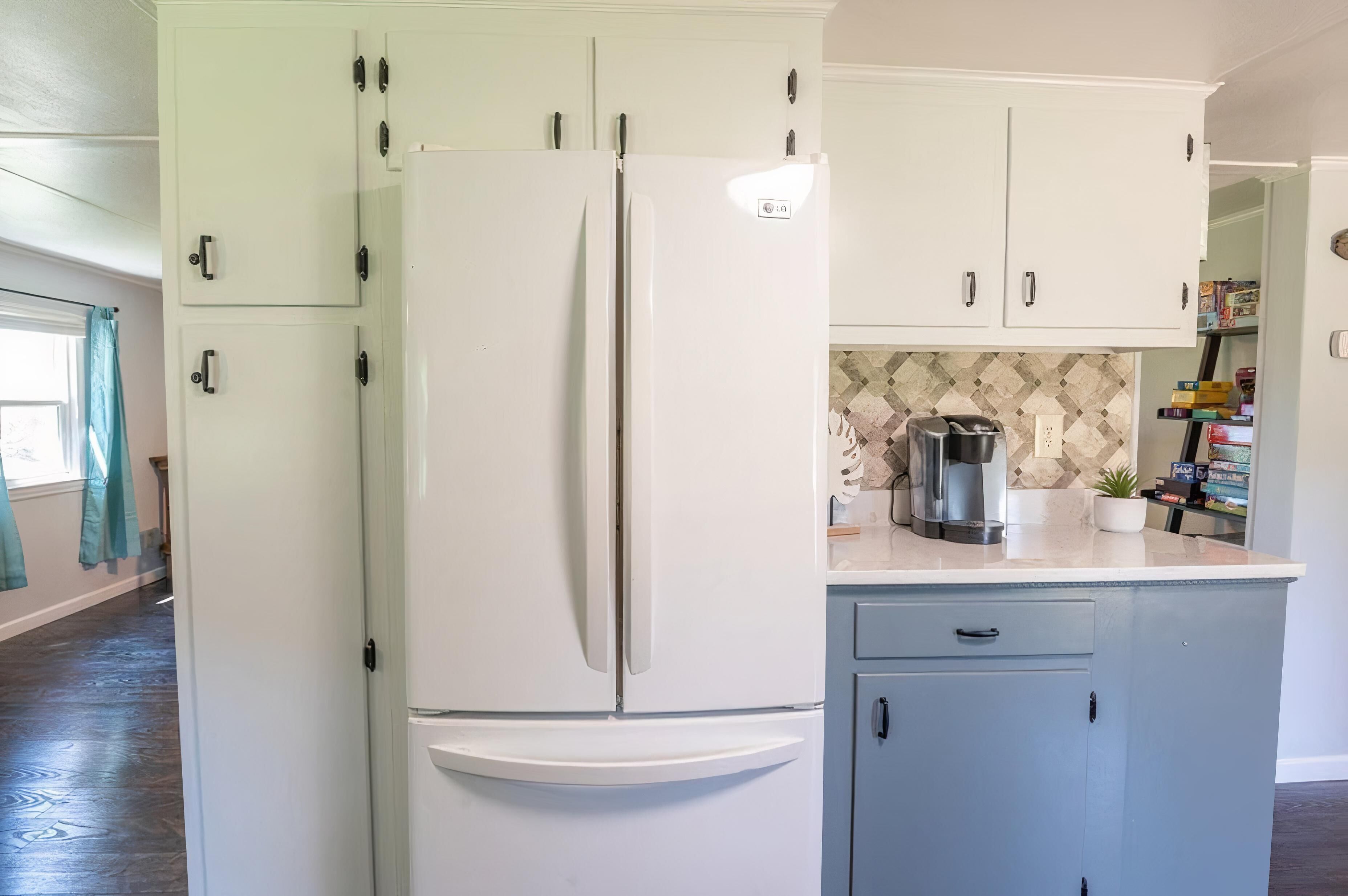 A kitchen with white cabinets, a white refrigerator, and a coffee maker on the counter.