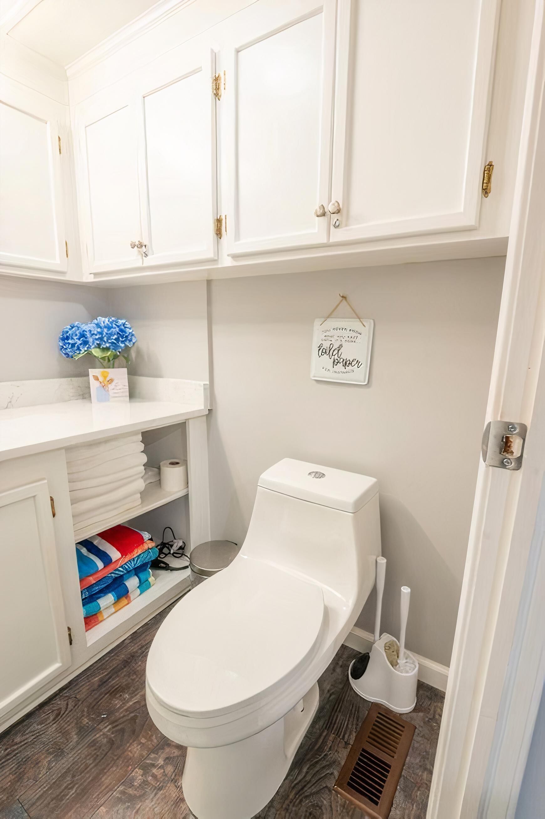 Un baño con armarios blancos, un inodoro, una ducha y un perchero para toallas.