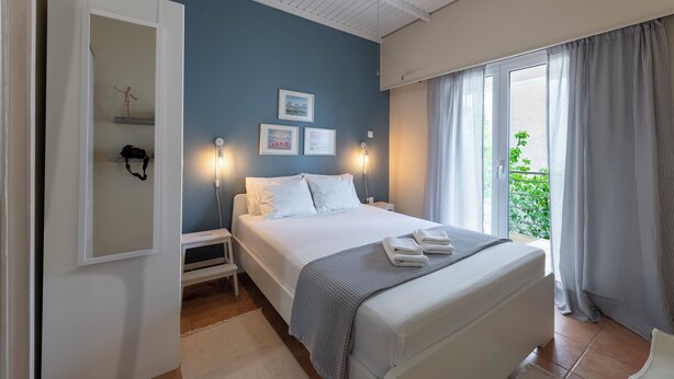 Un dormitorio con cama, mesitas de noche, cortinas y vistas al exterior.