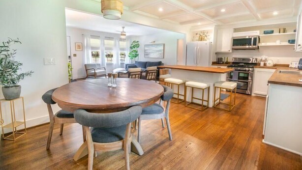 A modern kitchen with a central island, wooden flooring, and white cabinetry. - Paramount Paradise: Stylish + Screen Porch! (North Charleston)