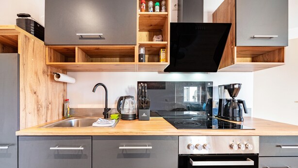A modern kitchen with a wooden countertop, stainless steel appliances, and a built-in oven. - Apartment 'Backstuff' with Wi-Fi (Hambuch)