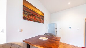 A dining area with a wooden table, a chair, a refrigerator, and a painting on the wall. - Apartment 'Backstuff' with Wi-Fi (Hambuch)