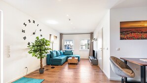 A modern living room with a sectional sofa, a coffee table, a potted plant, a clock, and a painting on the wall. - Apartment 'Backstuff' with Wi-Fi (Hambuch)