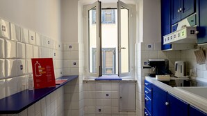 Eine Küche mit weißen Fliesen, einem Fenster mit Fensterläden, einem roten Schild und blauen Schränken.