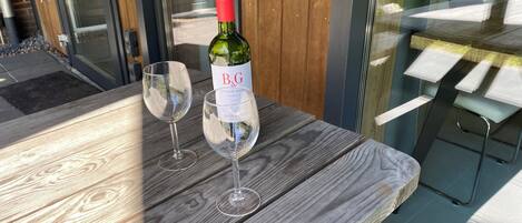 Una mesa de madera con dos copas de vino y una botella de B&G Pinot Noir Reserve 2022.