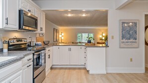 Una cocina moderna con armarios blancos, electrodomésticos de acero inoxidable y encimera de granito.