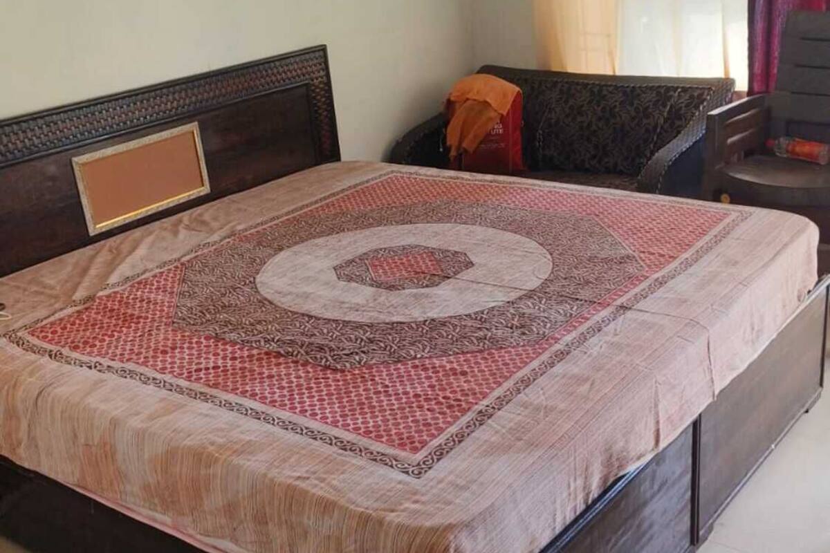 Una cama con colcha estampada, cabecera y estructura de madera.