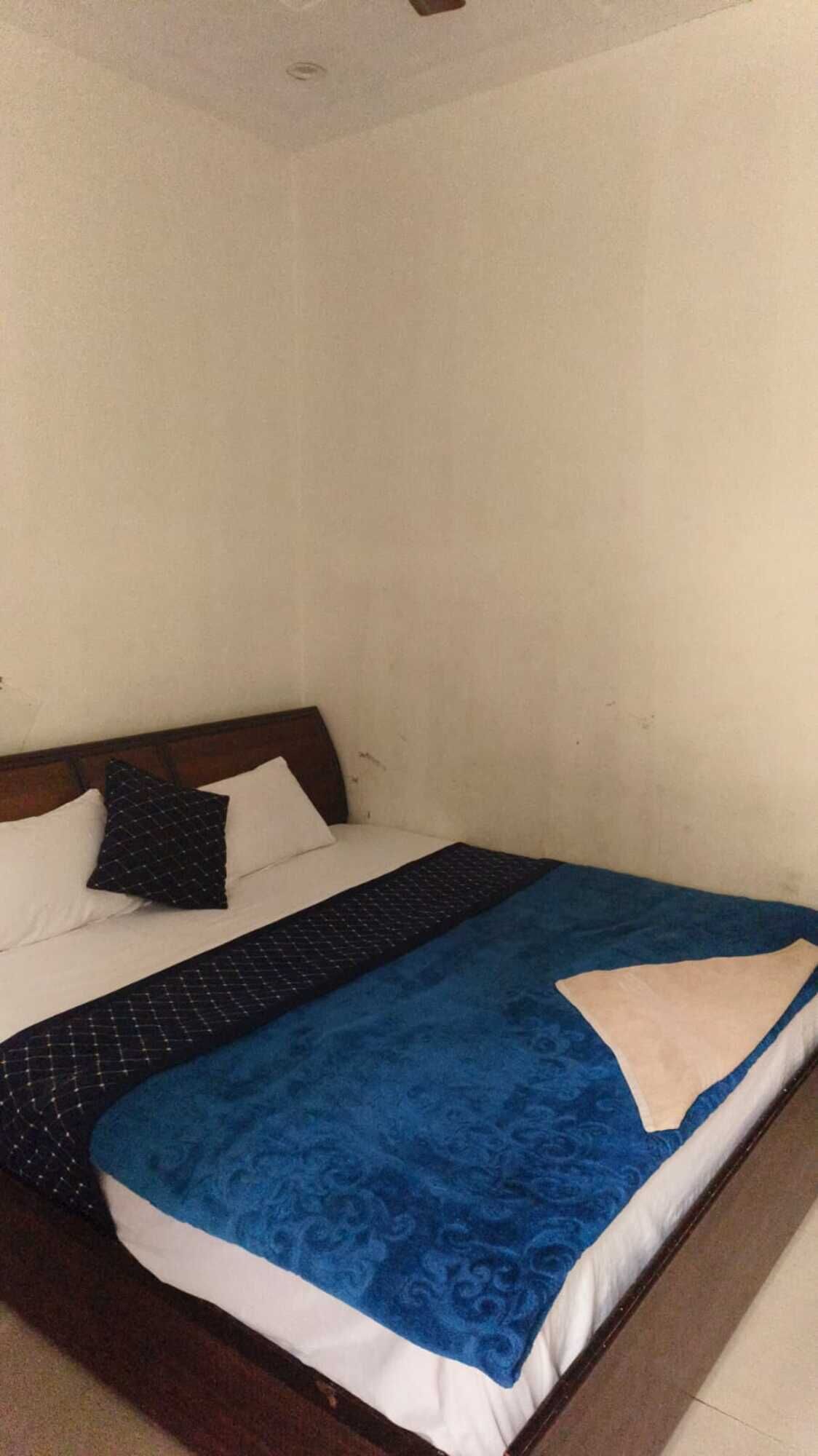 Un dormitorio con una cama, almohadas y una manta azul.