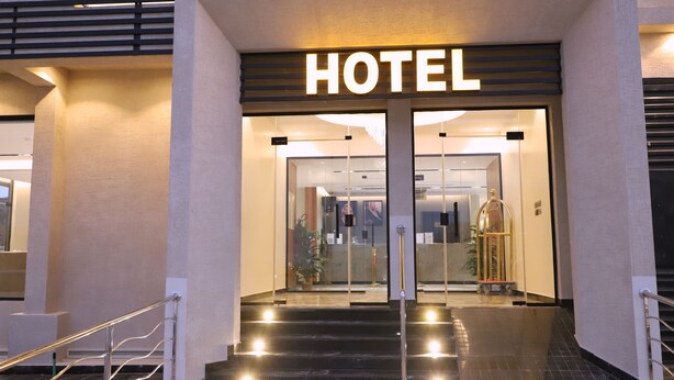 En hotelindgang med et moderne design, med et tydeligt 'HOTEL' skilt over dørene.