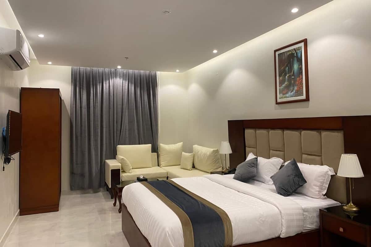 Ein modernes Hotelzimmer mit einem großen Bett, einer Sitzecke, einem Schreibtisch und einem Bild an der Wand.