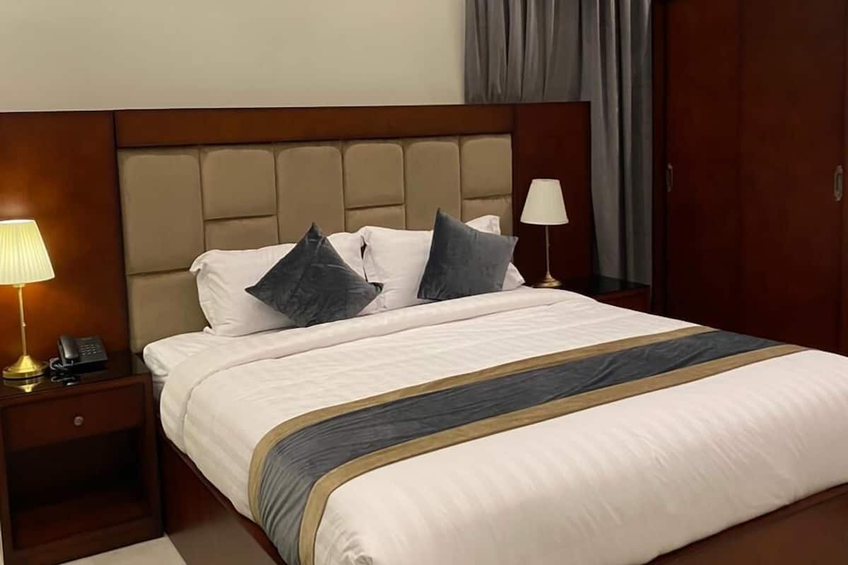 Ein Hotelzimmer mit einem großen Bett, einem Nachttisch mit Lampe, einer Klimaanlage und einem Kleiderschrank.