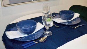 A table set with blue bowls, a glass with a water flower, and silverware on a dark blue tablecloth. - Cosy Urban Retreat in Leeds (Leeds)