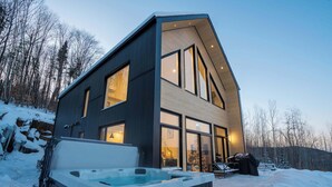 A modern two-story house with a hot tub in the front yard.