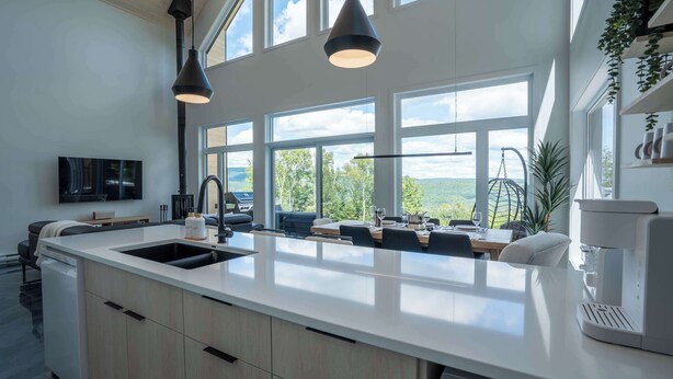 A modern kitchen with a large island, built-in appliances, and large windows offering a view of the outdoors.