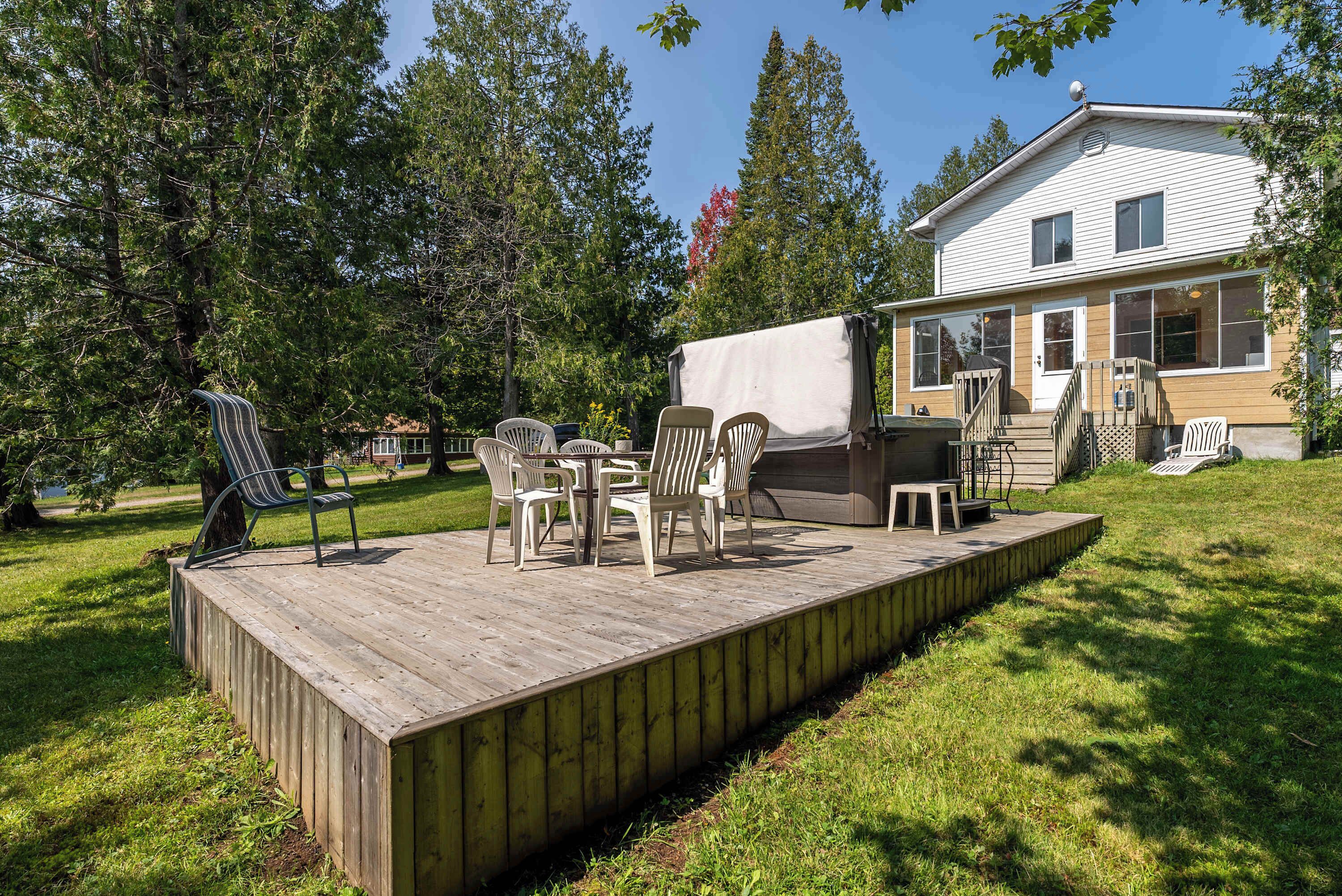 A wooden deck with outdoor furniture, a barbecue grill, and a covered area.