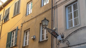Ein Gebäude mit mehreren Fenstern und Türen, einige davon mit Fensterläden, und einer Straßenlaterne.