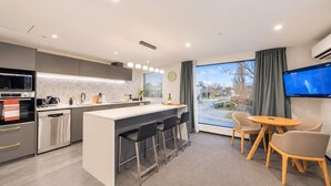 Una cocina moderna con una isla central, taburetes de bar y un área de comedor con televisor.