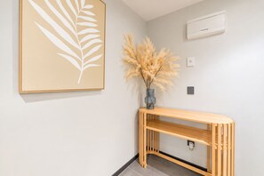 A minimalist room with a wooden console table, a framed leaf artwork, and a vase with dried pampas grass.